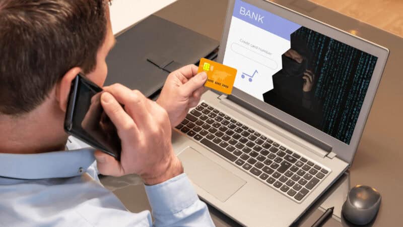 Man holding his credit card and on the phone with his bank