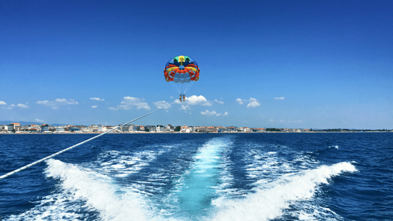 Parachute carrying parasailers behind a boat