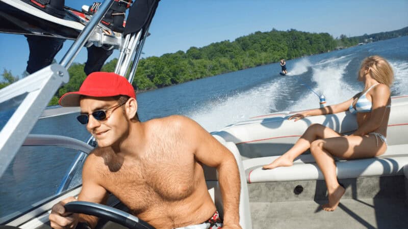 A couple on a motorboat pulling a water skiier.