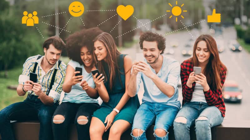 Five young people looking at their phones. Symbols for like and share overhead.