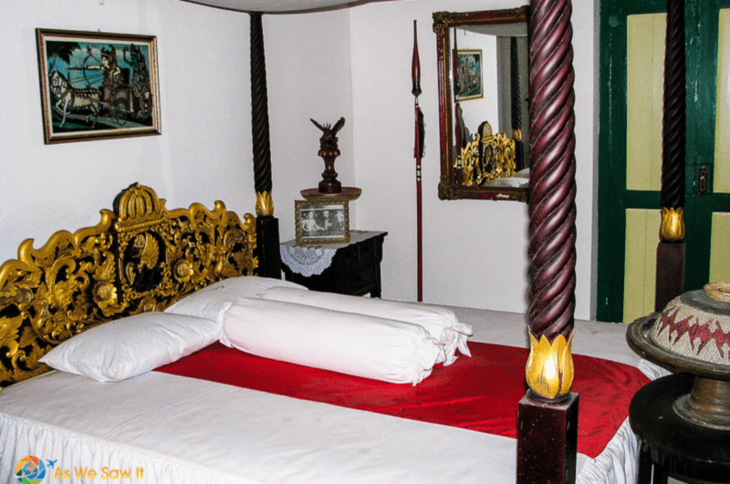 Luxurious carved Balinese four poster bed and headboard with gold leaf in a bedroom in Bali