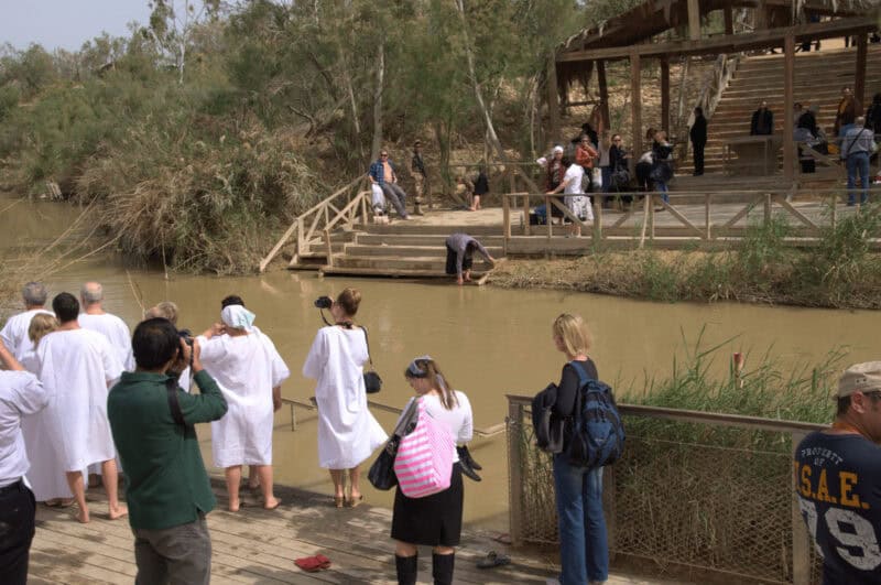 People in white robes gather for a baptism at the Jordan River
