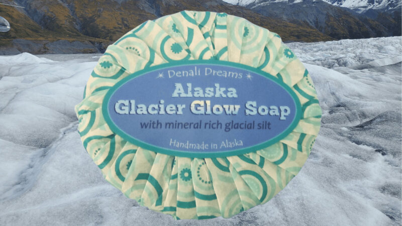 Bar of Alaska Glacier Glow Soap with mineral rich glacial silt makes for a cheap souvenir. Background image is of the silt-covered Knik Glacier.