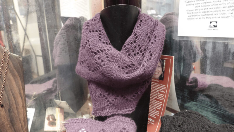 Shop display featuring a purple quiviut knit scarf and hat alongside a waffle blanket.