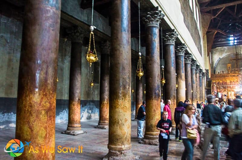 Visitors walking past the ancient marble columns lining the nave of the Church of the Nativity.