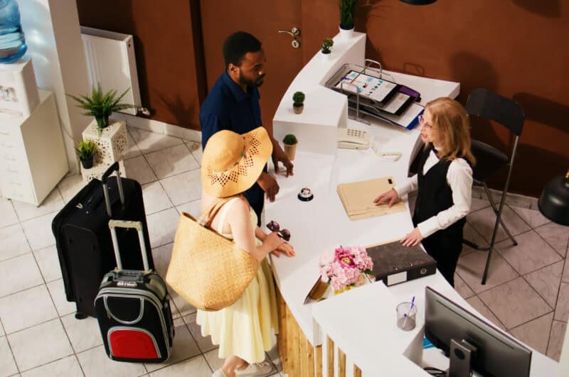 Travelers with suitcases talking to a desk clerk