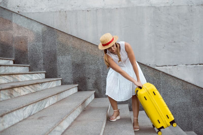 A woman lugging a heavy suitcase up stairs