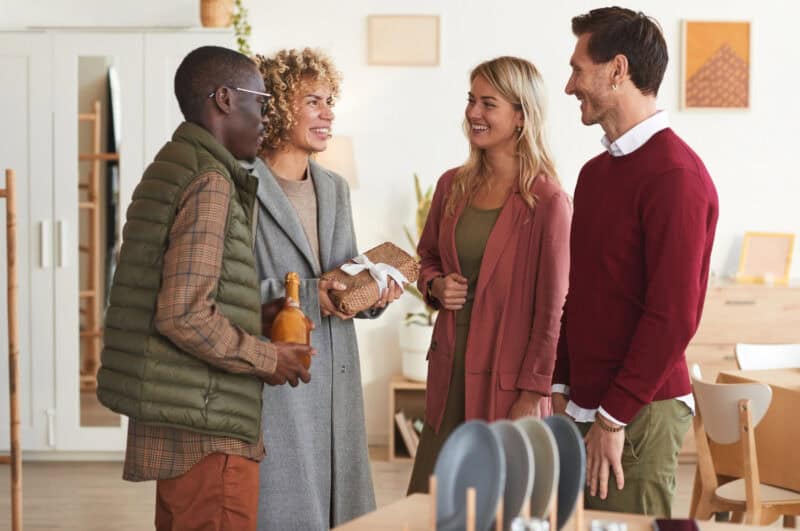 A couple welcoming guests, who are bringing a gift