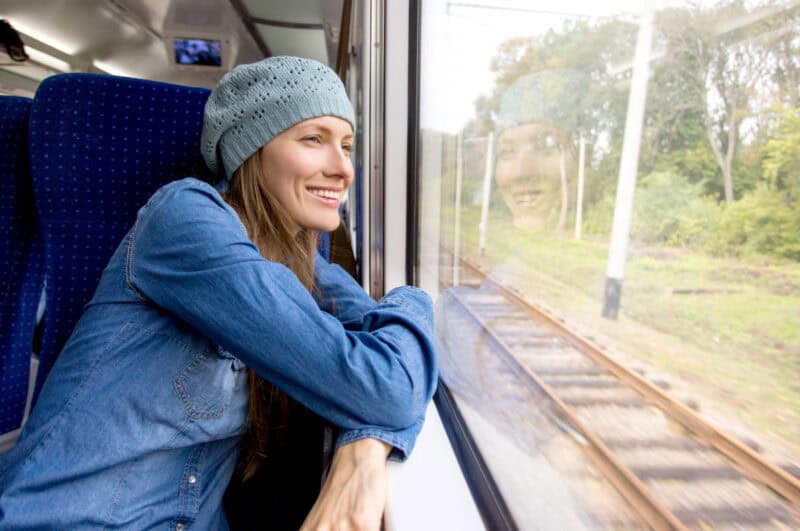 Young woman traveling by train and looking out the window