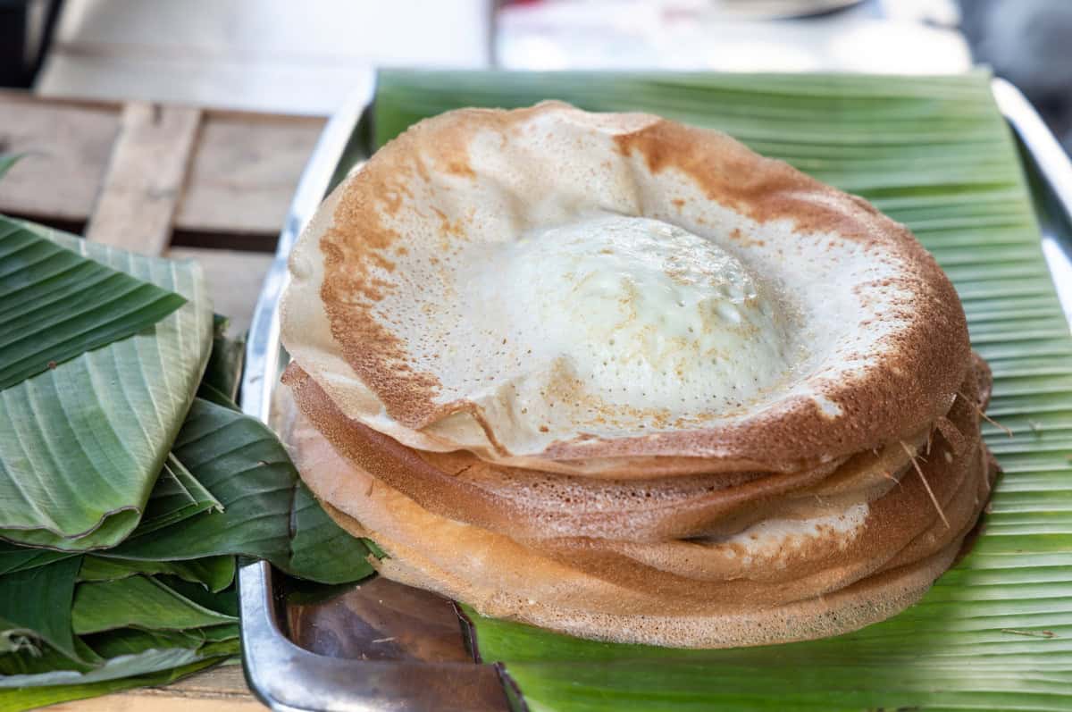 a stack of apom manis treats witih a banana leaf on a metal tray