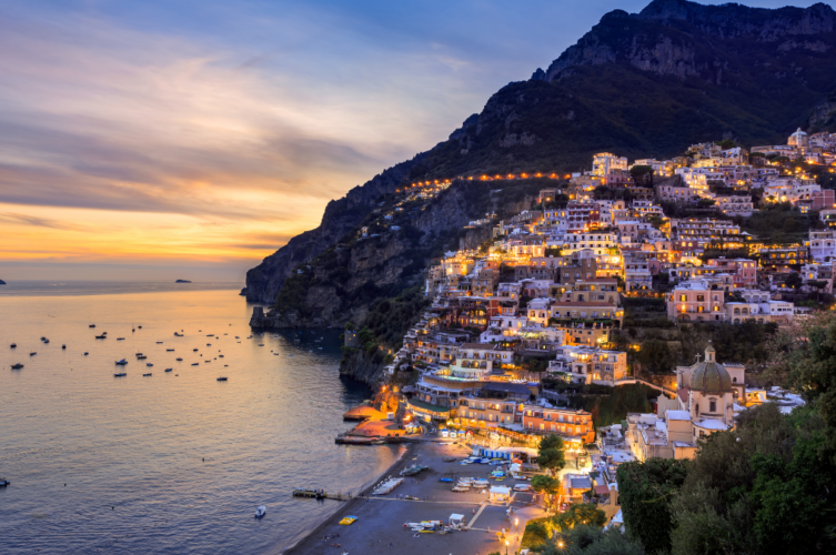 Sunset view of Positano’s steep cliffside buildings along the Amalfi Coast