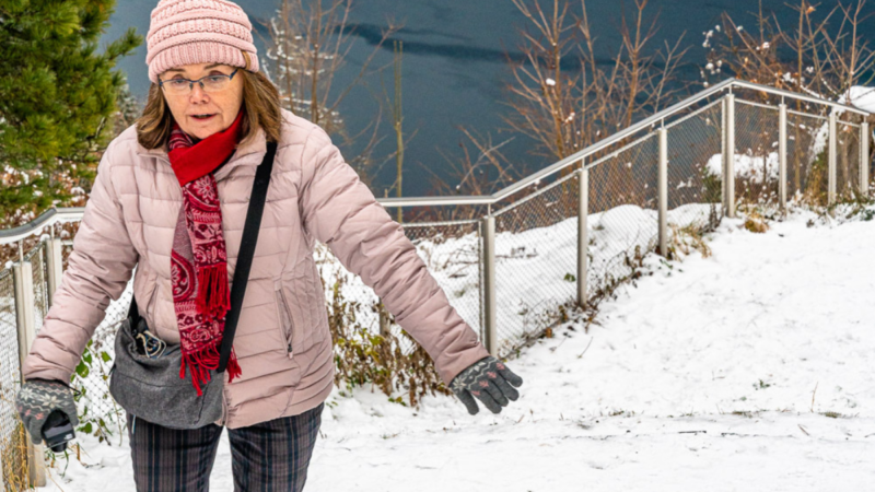 Linda walking in snowy Hallstatt with a crossbody bag and camera