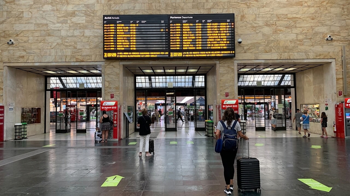 Traveler with luggage beneath the departure boards at Firenze Santa Maria Novella train station