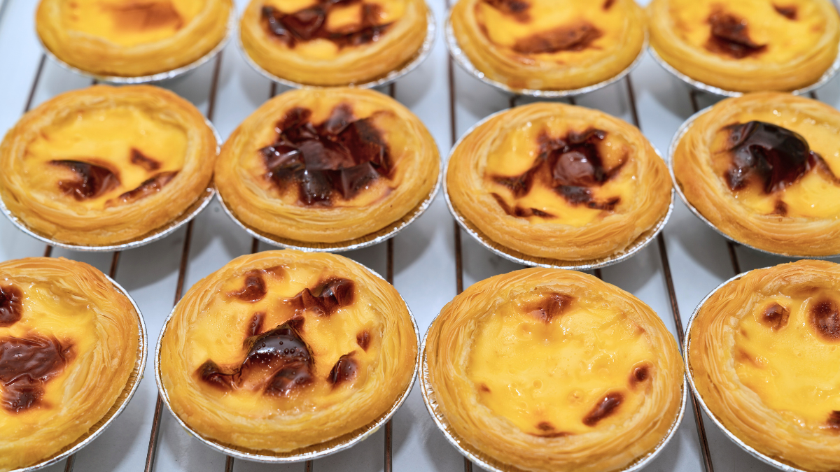 Fresh Hong Kong-style egg tarts cooling on a wire rack.
