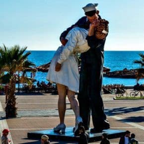 People standing around a statue of a sailor kissing a nurse on Civitavecchia's waterfront.