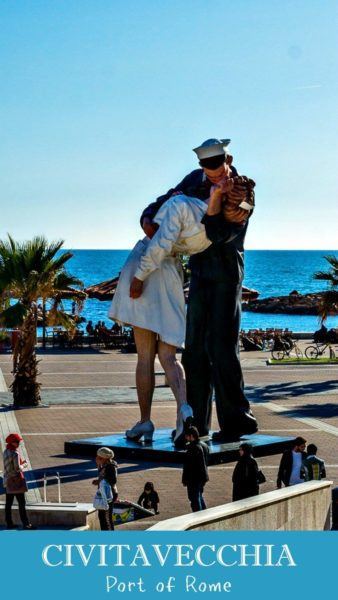 People standing around a statue of a sailor kissing a nurse on Civitavecchia's waterfront.