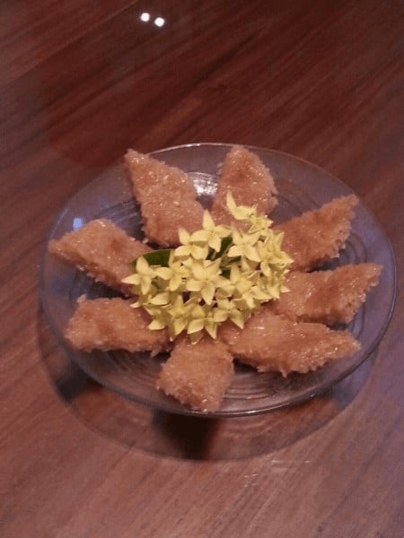 A plate of homemade kue wajik, decorated with yellow flowers