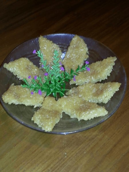 A plate of homemade kue wajik, decorated with purple flowers