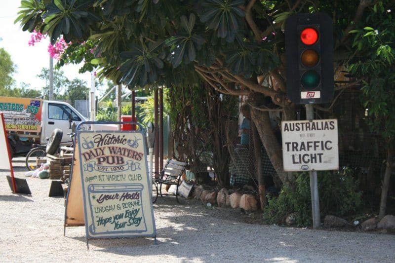 Australian outback town sign says Historic Daly Waters Pub est. 1930. Nearby stoplight says Australia's most remote traffic light.